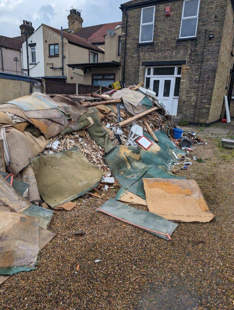 Builders waste piled in a garden, ready for disposal by Essex Waste Man during a builders waste removal service near Essex and London postcodes.