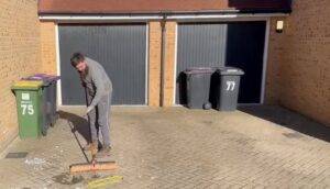Essex Waste Man worker sweeping rubbish during a rubbish removal service near Essex and London postcodes.