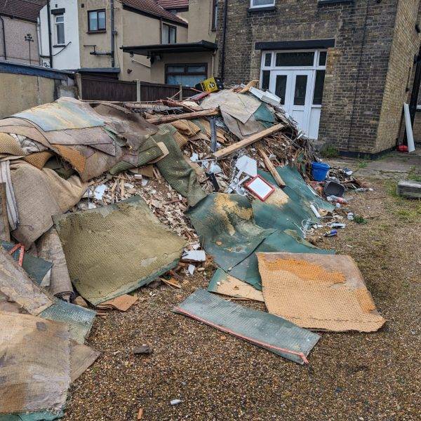 Builders waste piled in a garden, ready for disposal by Essex Waste Man during a builders waste removal service near Essex and London postcodes.